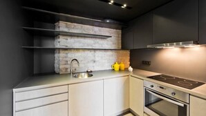 Eine moderne Küche mit Einbauherd, Spüle und einer Wand mit Backsteinverkleidung.