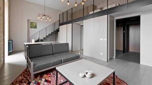 Ein modernes Interieur mit einem grauen Sofa, einem weißen Tisch und einem gemusterten Teppich.