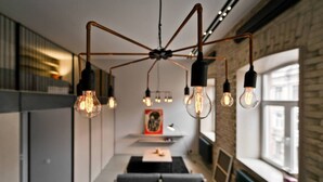 Ein modernes Interieur mit freiliegenden Ziegelwänden, einem langen Esstisch und hängenden Edison-Lampen.