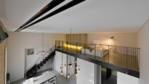 Ein modernes Interieur mit einer Treppe zu einem Erkerbereich, einem Essbereich und einer hängenden Leuchte.
