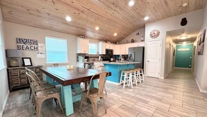 Una cocina moderna con una isla central, techo de madera y vista al área de estar.