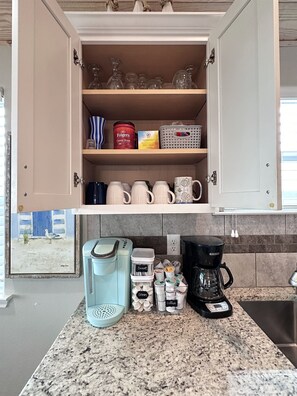 A kitchen with a coffee maker, a blender, and a coffee pot on the counter.