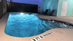 Una piscina con un cartel que indica una profundidad de 1 metro 17 centímetros, rodeada por una cerca de madera y un edificio con una puerta.