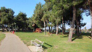 A park with a paved path, benches, and playground equipment. - Apartment Nautica (Novigrad)