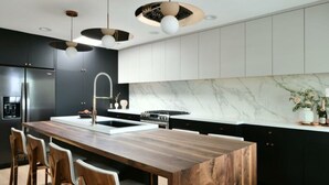 Une cuisine moderne dotée d’un îlot central en bois, d’appareils électroménagers en acier inoxydable et de luminaires suspendus.