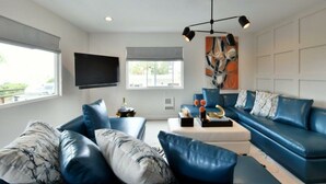 Un salon moderne avec un canapé d’angle, une table basse et un téléviseur à écran plat fixé au mur.