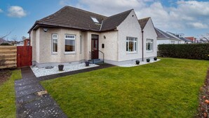 A two-story house with a sloped roof, a front door, and a small front yard with a pathway leading to the entrance. - Sunset View - Donnini Apartments (Ayr)