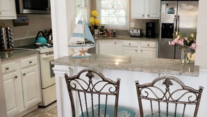 A kitchen with white cabinets, a stainless steel refrigerator, a coffee maker, and a small sailboat decoration. - Wildlife Watching! Lagoon & Golf view, beach gear included. Peaceful & Private! (Hilton Head Island)