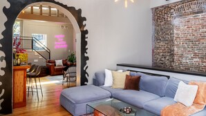 Un salon moderne avec un grand canapé d’angle, une table basse en verre et un mur décoratif en briques.