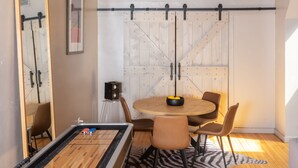 Une pièce chaleureuse avec une table de billard, un ventilateur de plafond en bois et un luminaire moderne.
