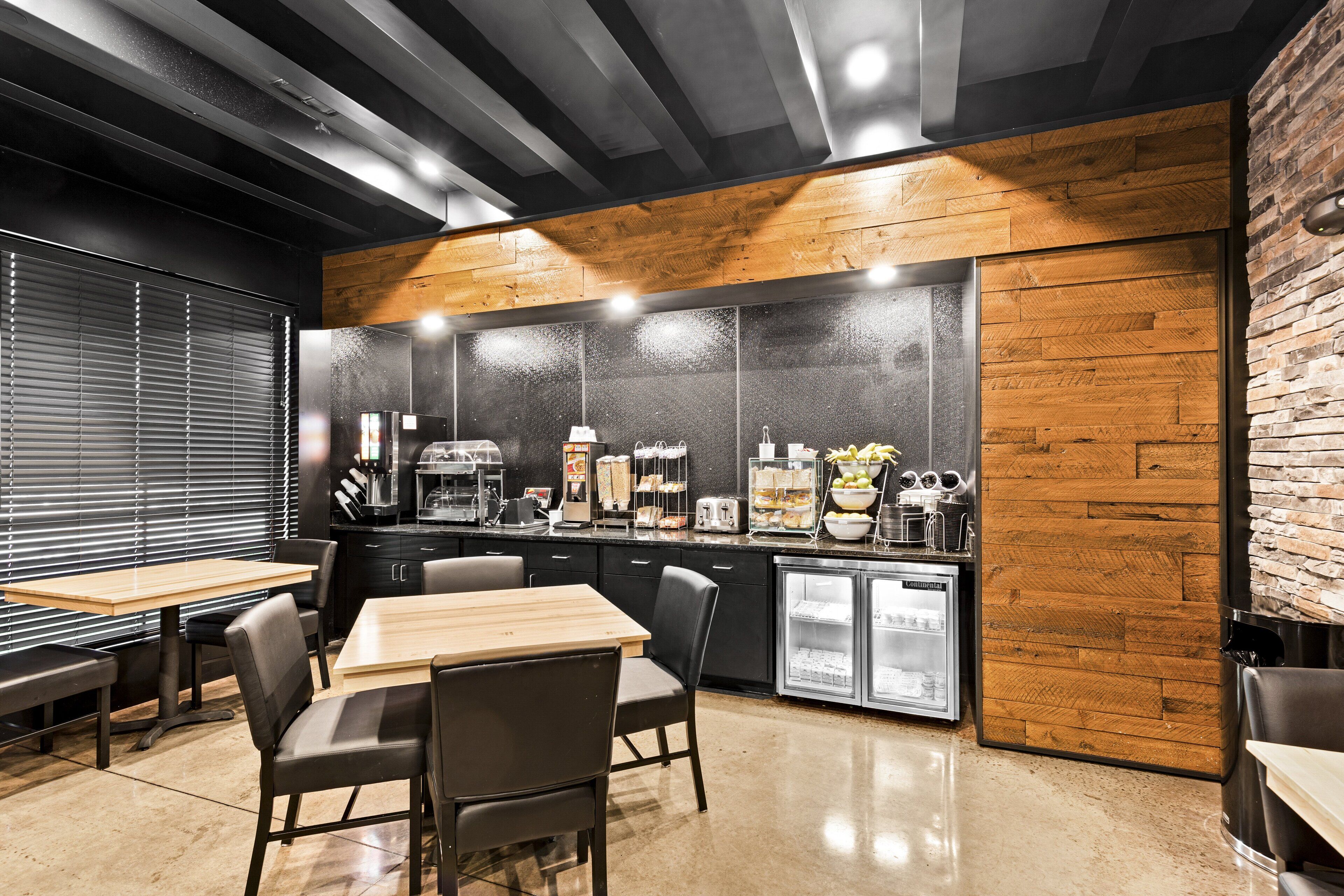 A modern kitchen with wooden accents, a refrigerator, and a coffee station.