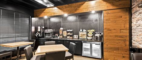 A modern kitchen with wooden accents, a refrigerator, and a coffee station.