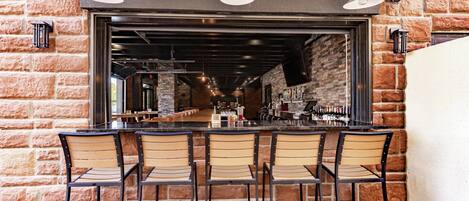 A bar area with a brick wall, a counter, and four bar stools.