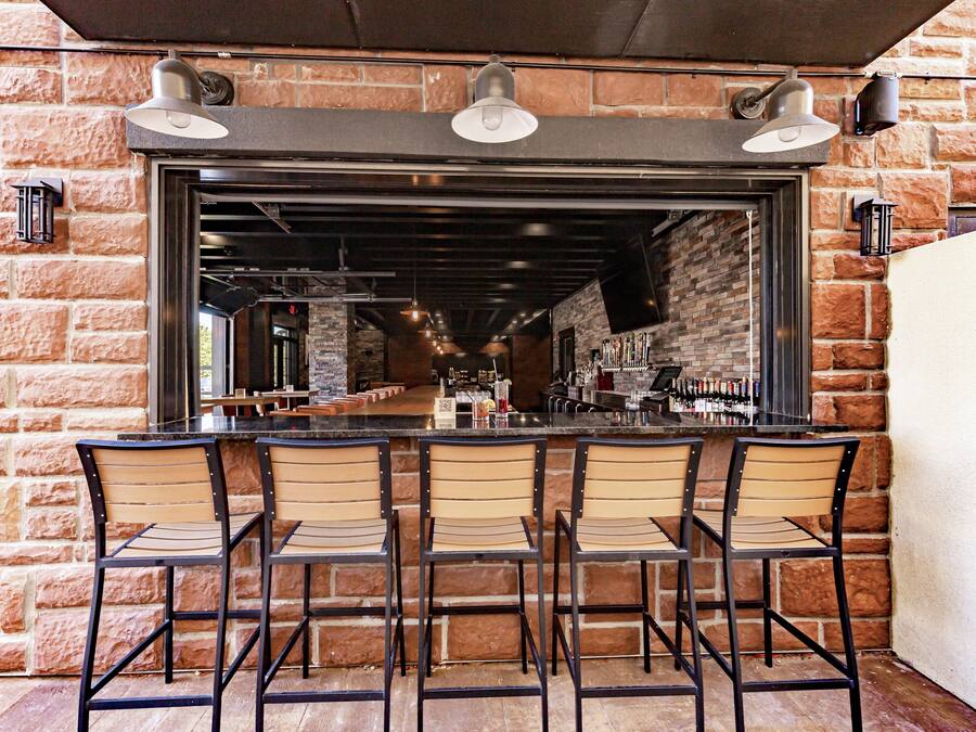 Una zona de bar con pared de ladrillo, una barra y cuatro taburetes.
