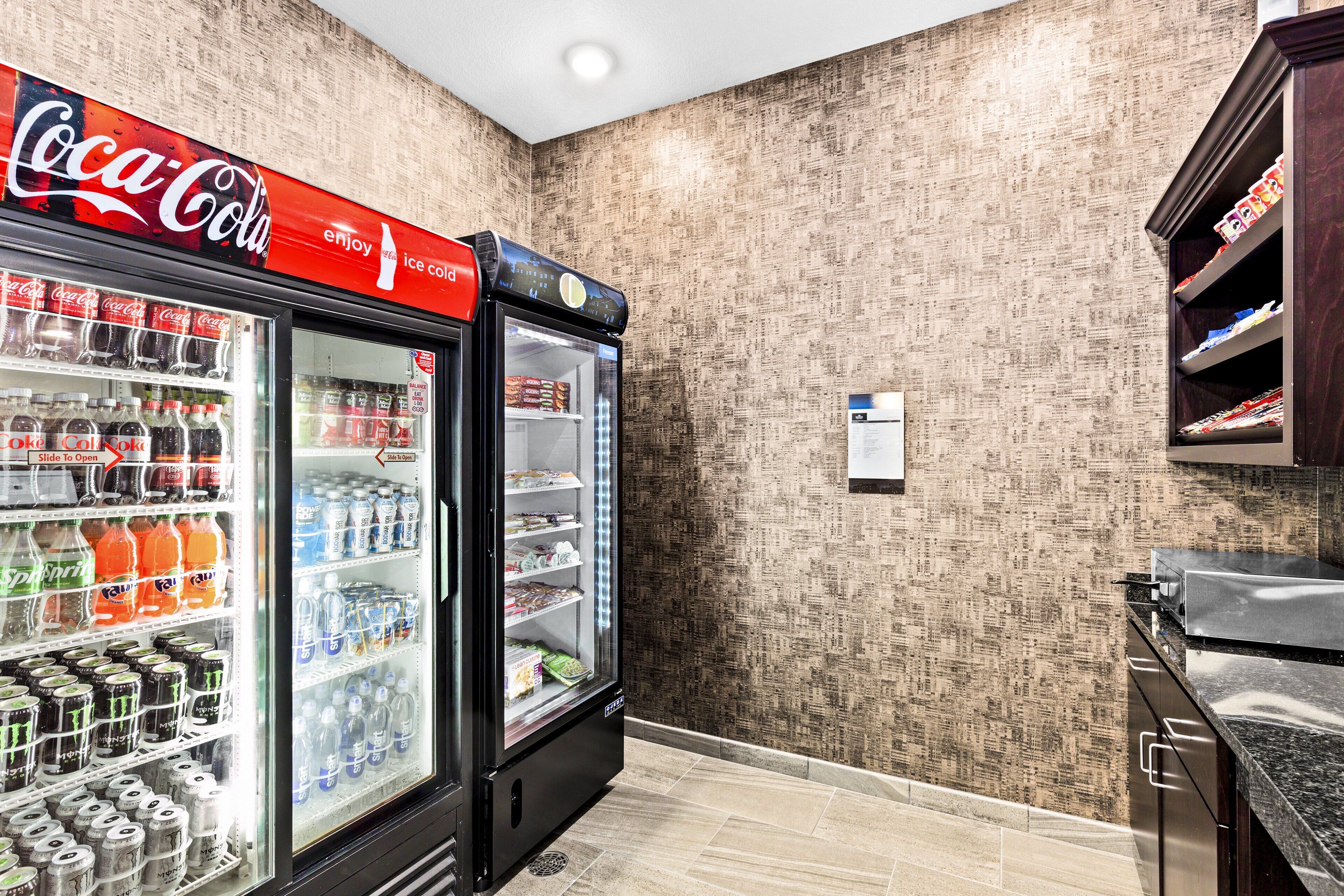 Un refrigerador de Coca-Cola lleno de diversas bebidas, un suelo de baldosas y una pared con estampado.