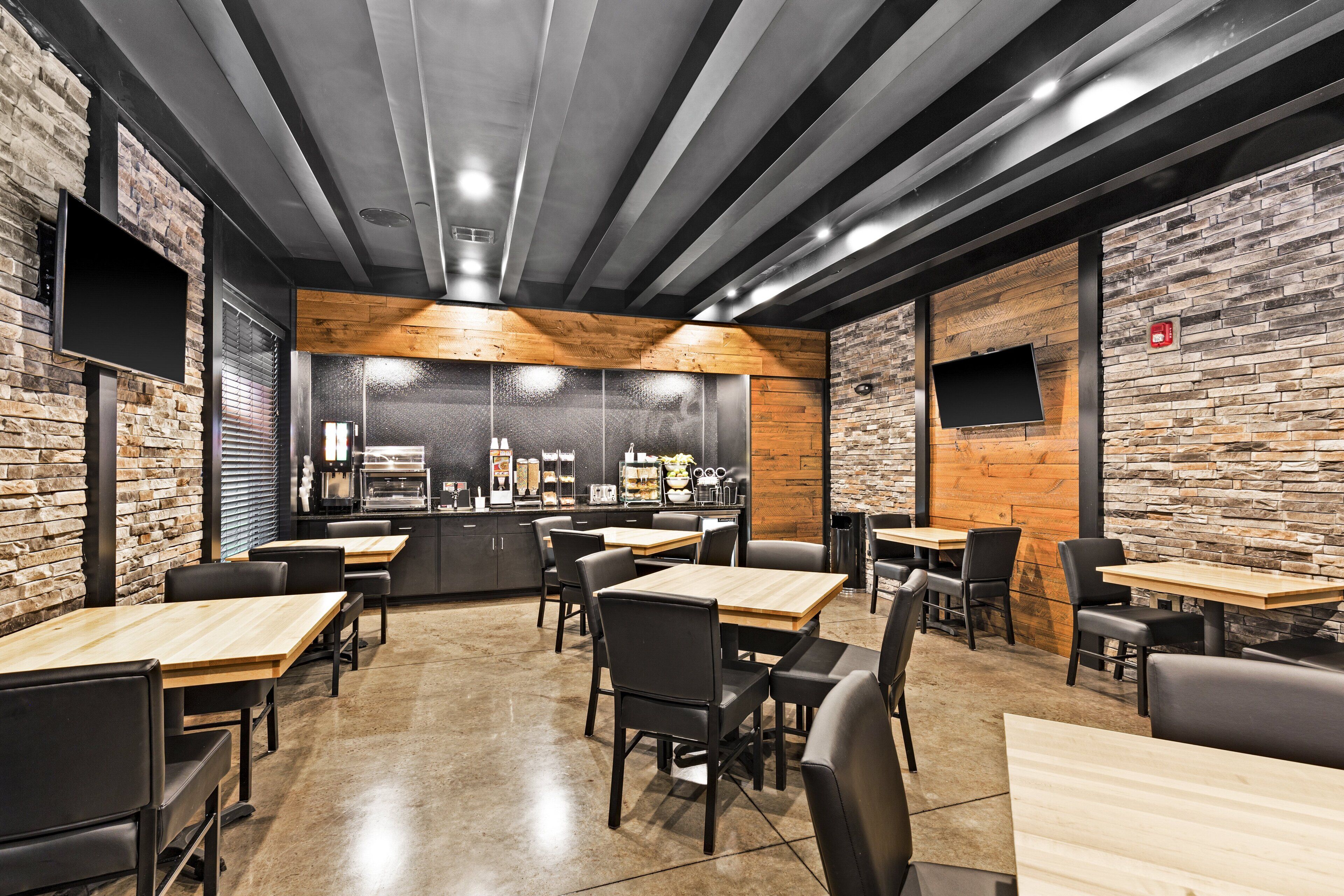 A modern restaurant with brick walls, wooden accents, and black leather chairs.
