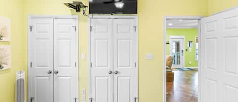 A room with two white doors, a ceiling fan, and a television mounted above.