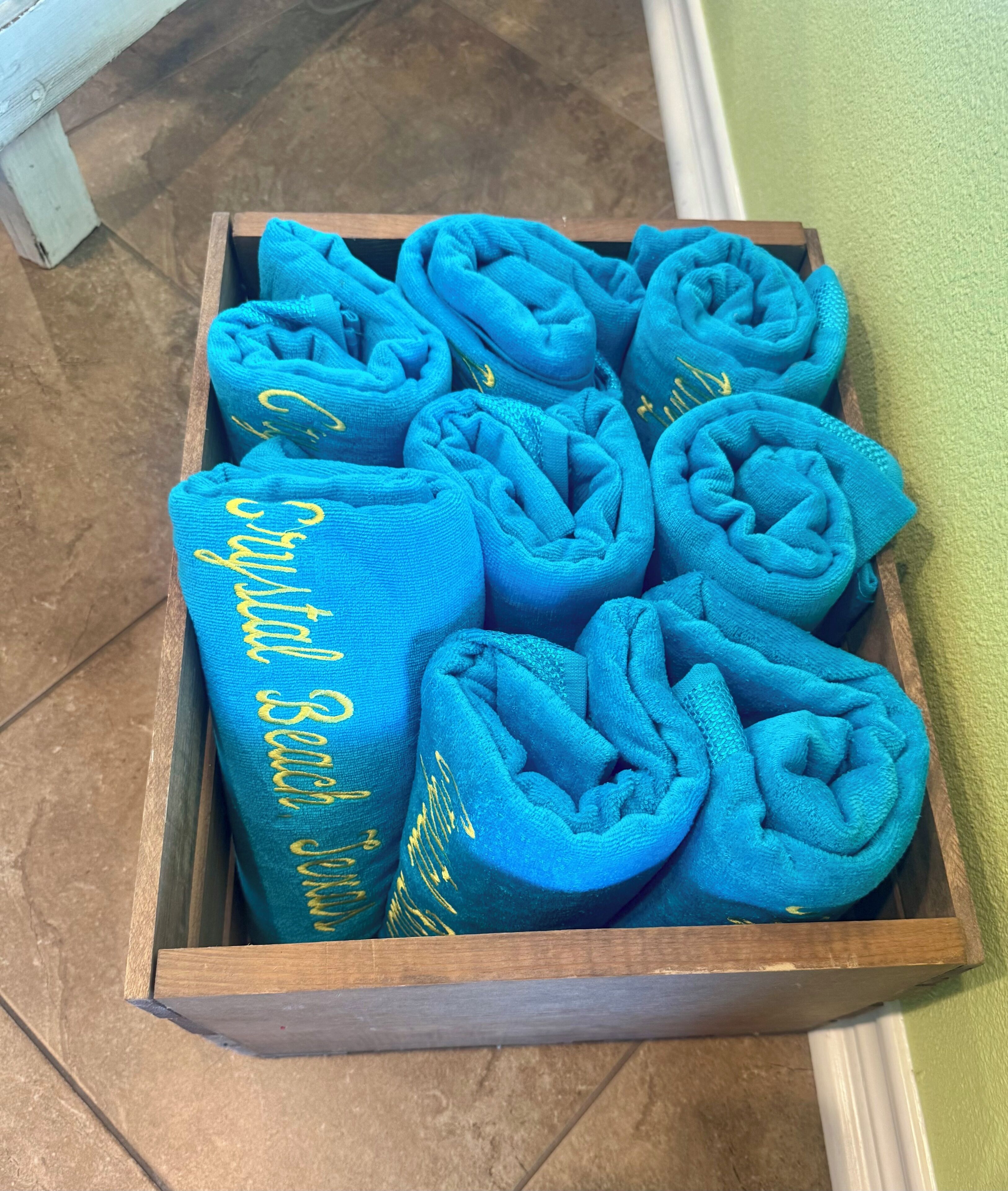 A wooden box filled with rolled blue towels.