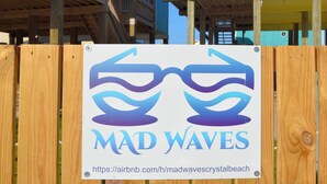 Ein Schild mit der Aufschrift 'Mad Waves' und einer URL für die Buchung von Unterkünften.