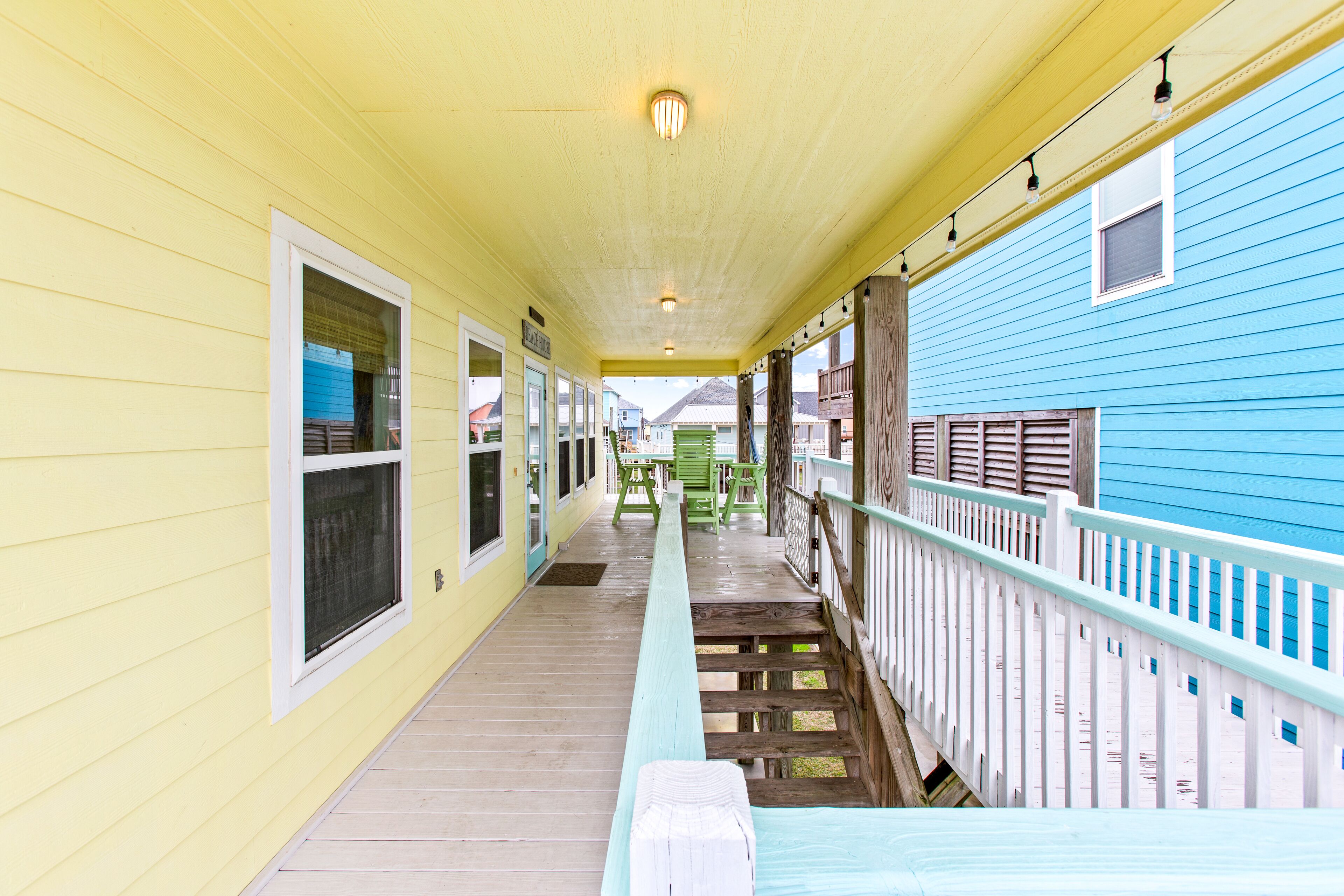 A covered porch with a wooden bench, a railing, and a view of the surrounding buildings.