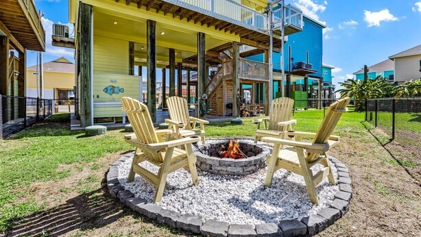 Ein Gebäude mit überdachter Veranda, einer Sitzgelegenheit im Freien mit Adirondack-Stühlen und einer Feuerstelle.
