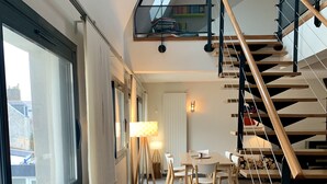 A modern interior with a staircase, a dining area, and a view through a window. - Le loft Concarneau (Concarneau)