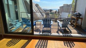 A balcony with blue Adirondack chairs, a small round table, and a grill. - Le loft Concarneau (Concarneau)