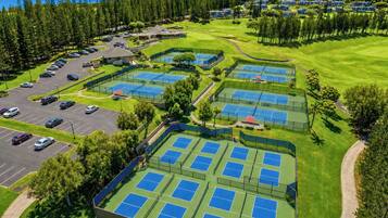 Vue aérienne d’un terrain de golf avec plusieurs courts de tennis, un parking et des espaces verts environnants.