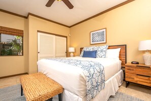 Une chambre à coucher avec un grand lit, une table de chevet avec une lampe, un banc et une fenêtre avec des stores.