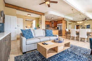 A modern living room with a grey sofa, wooden coffee table, and a blue patterned rug.