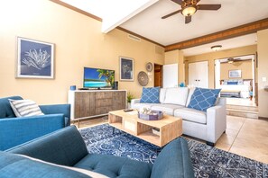 Ein Wohnzimmer mit Fernseher, Sofas, einem Couchtisch und einem Essbereich mit Tisch und Stühlen.