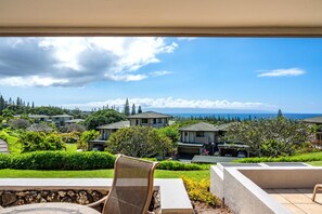 A residential area with houses, a view of the ocean, and a patio with a chair.