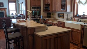 A spacious kitchen with wooden cabinets, a central island, and pendant lighting. - Welcome Hall 5 bedroom 1880’s home on 55 acres (Paris)