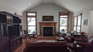 A spacious living room with a fireplace, wooden flooring, and large windows. - Welcome Hall 5 bedroom 1880’s home on 55 acres (Paris)