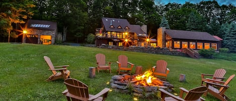 A lodge with a fire pit and Adirondack chairs in the yard.