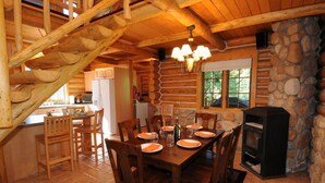 A rustic cabin interior with a dining area, kitchen, and stone wall. - Secluded mountain hideaway just outside of Bozeman (Bozeman)