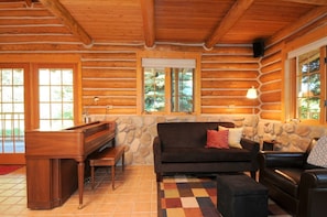 Cozy cabin interior with a desk for work, a sofa for relaxation, and a window offering a view of the surrounding greenery.
