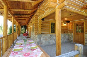 Relax on the covered porch with a dining table set amidst a charming log cabin.