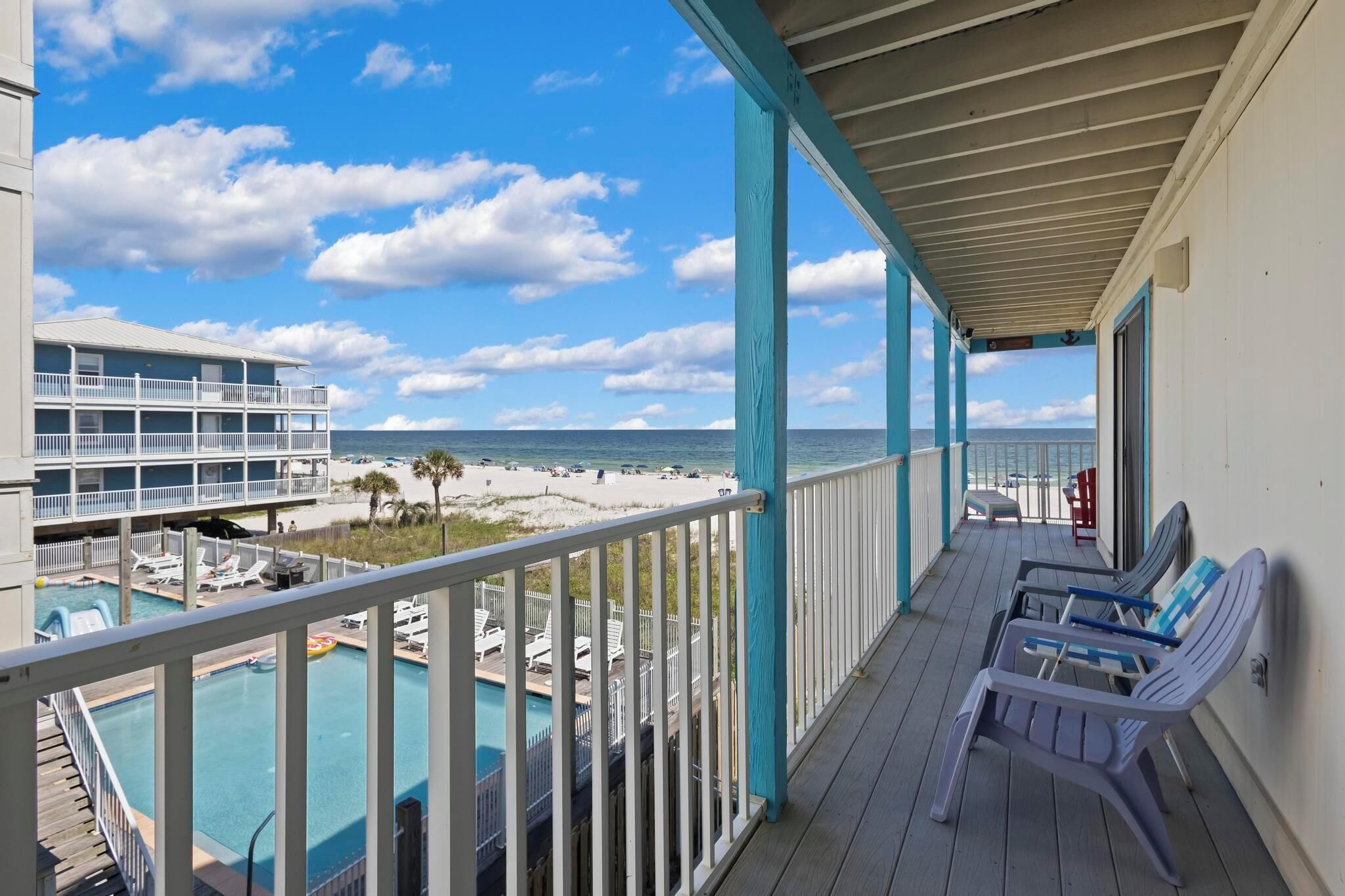 A balcony with a view of a beach and a pool area.