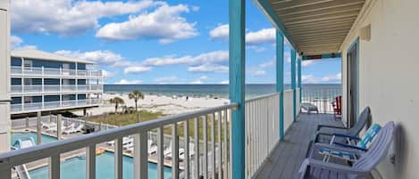 A balcony with a view of a beach and a pool area.