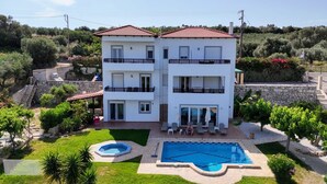 Um edifício de dois andares com piscina, jardim e escadaria que dá acesso ao andar superior.