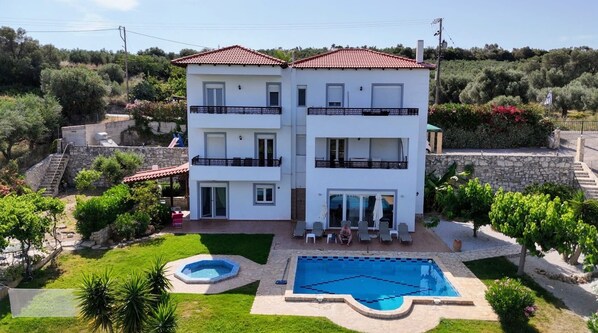 Un edificio a due piani con piscina, giardino e una scala che conduce al piano superiore.