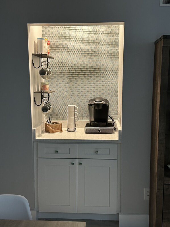 A kitchen with a built-in coffee station, including a Keurig coffee maker, a coffee grinder, and a mug holder.