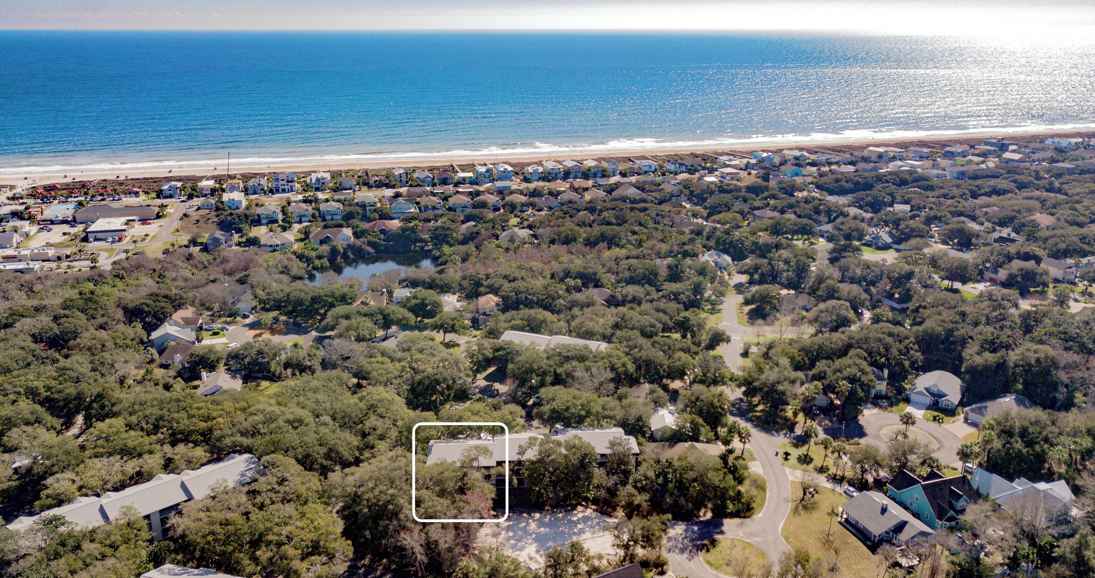 An aerial view of a coastal residential area with houses, roads, and a beach.