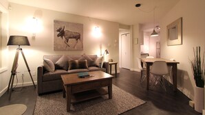 Ein Wohnzimmer mit einer Couch, einem Couchtisch und einem Bild eines Elchs. Es gibt einen Essbereich mit Tisch und Stühlen.