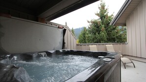 Ein Whirlpool auf einem Balkon mit Blick auf Bäume und Berge.