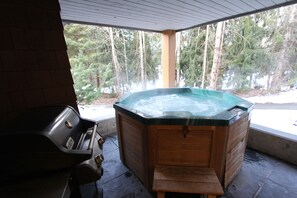 A hot tub under a covered patio with a grill nearby. - Glaciers Reach #66 | 2 Bedroom with Kitchen, Fireplace and Private Hot Tub (Whistler)