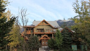 Ein großes, mehrstöckiges Holzhaus mit einem Balkon und Blick auf die Berge im Hintergrund.