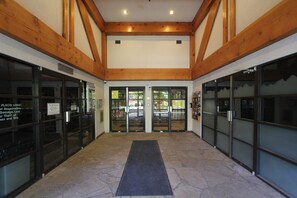 Un vestíbulo con piso de piedra, vigas de madera y puertas de vidrio.