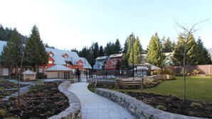 Zona residencial con un camino pavimentado, muros de contención de piedra y casas con fachadas rojas y azules.